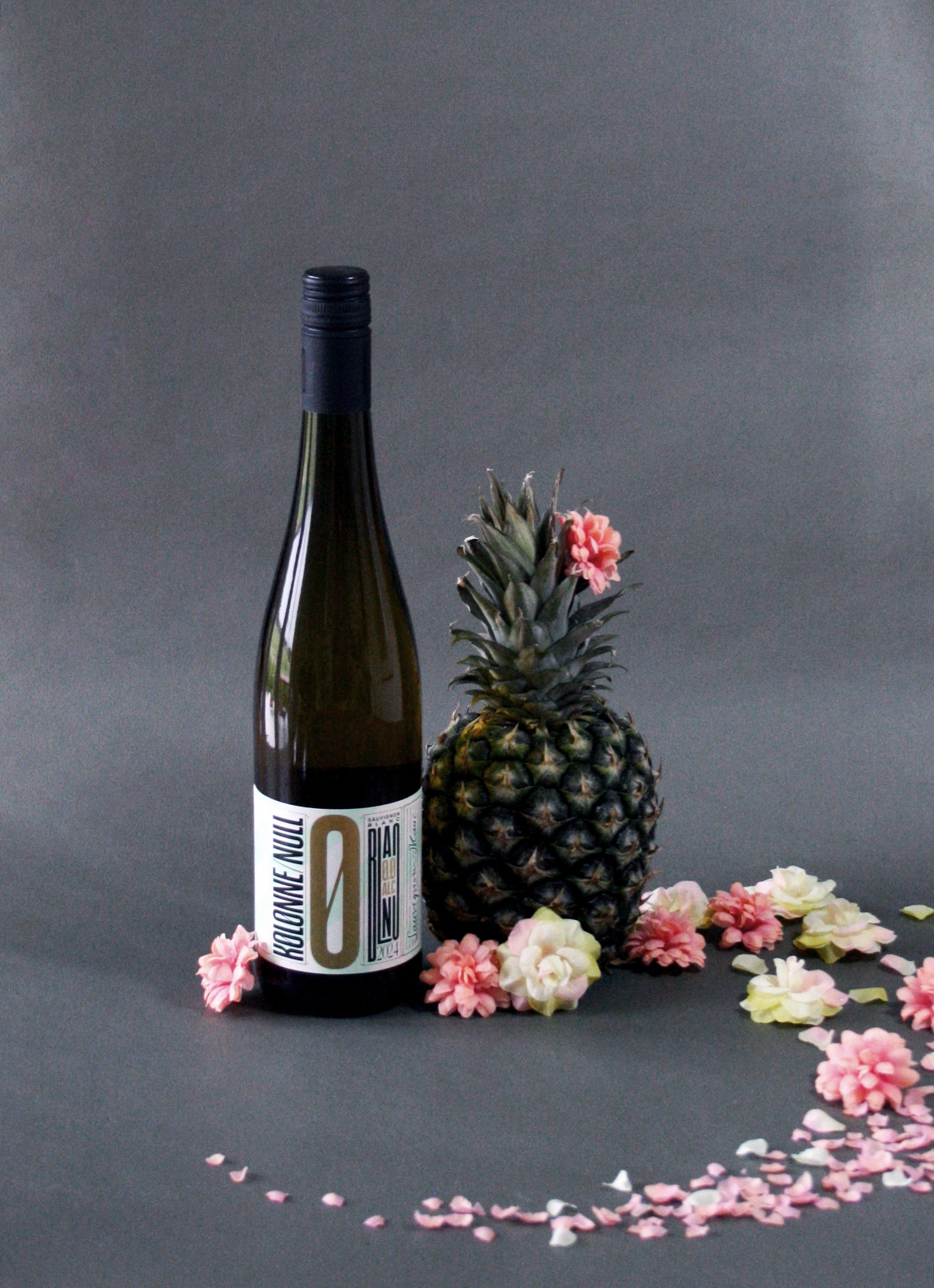 Bottle of Kolonne Null Sauvignon Blanc White Wine styled with flowers and a pineapple.