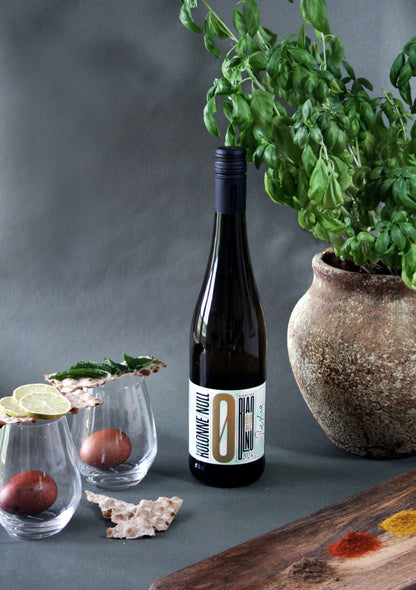 Wine bottle with a label on a table with glasses and a plant