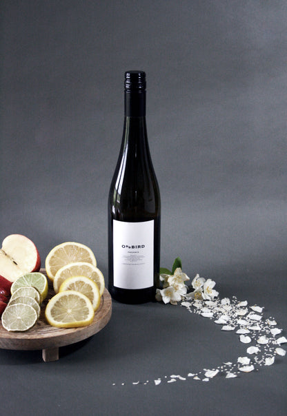 Wine bottle with a label on a dark surface with fruit and flowers